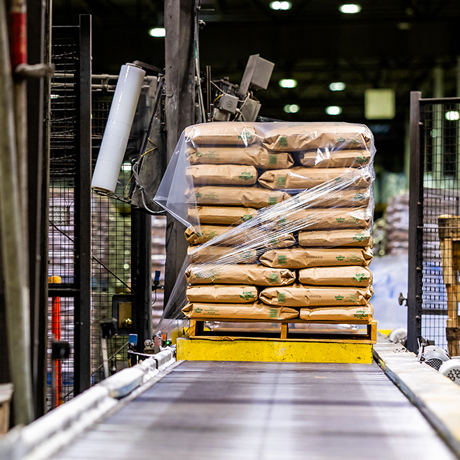 A pallet of branded U.S. Sugar kraft paper bags being stretch-wrapped on an automated conveyor line inside the Savannah refinery, representing the company's commitment to continuous improvement and scalable production